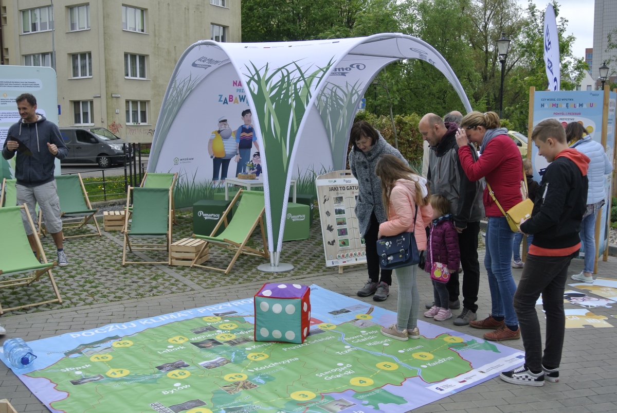na ziemi rozłożona kolorowa gra planszowa w ramach projektu „Pomorscy czują klimat”, dookoła stoją ludzie