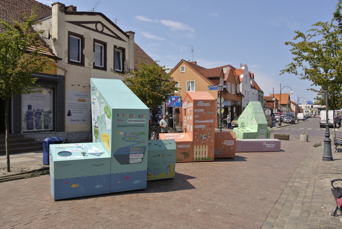 Interaktywna wystawa plenerowa w Łebie, na głównej ulicy w  Łebie stoją trzy bryły tworzące wystawę oraz ławka