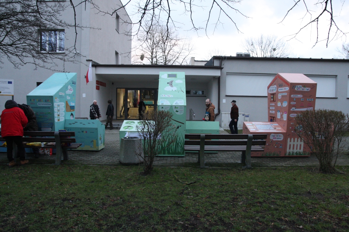 Trzy bryły tworzące interaktywną wystawę plenerową przed budynkiem Pomorskiego Zespołu Parków Krajobrazowych w Słupsku, dookoła ludzie