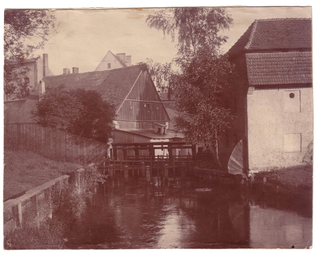 archiwalne zdjęcie Młyna Zamkowego; na czarno-białym zdjęciu: budynki oraz kanał rzeki Słupi