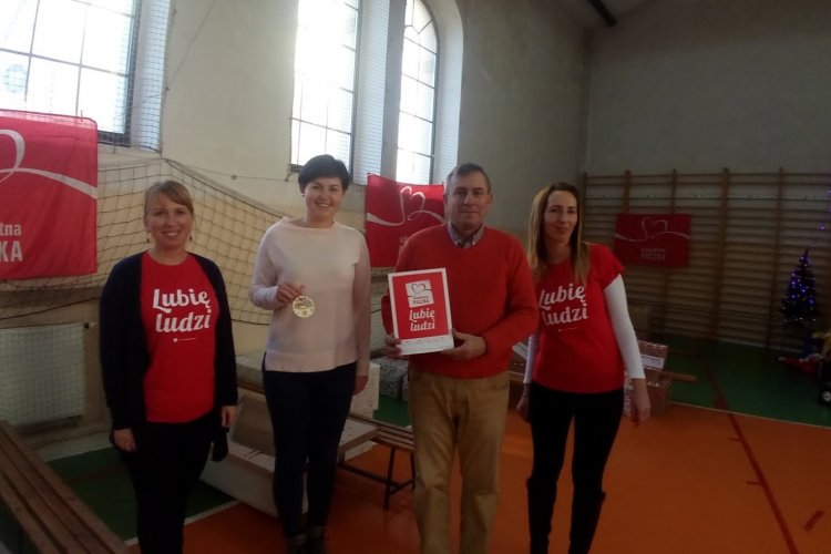 Sala magazynu Szlachetnej Paczki w Kwidzynie; na środku stoją cztery osoby osoby: dwoje pracowników WFOSiGW w Gdańsku oraz dwie wolontariuszki Szlachetnej Paczki