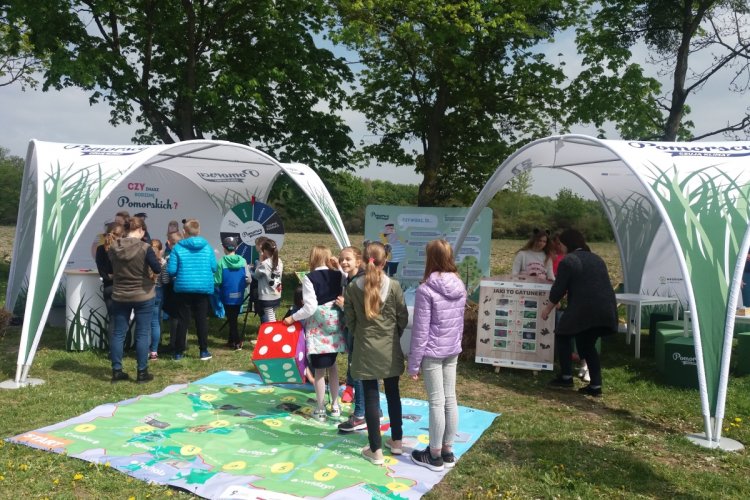 Dwa namioty stanowiska Pomorskich podczas pikniku przyrodniczego w Wojanowie, dookoła dzieci