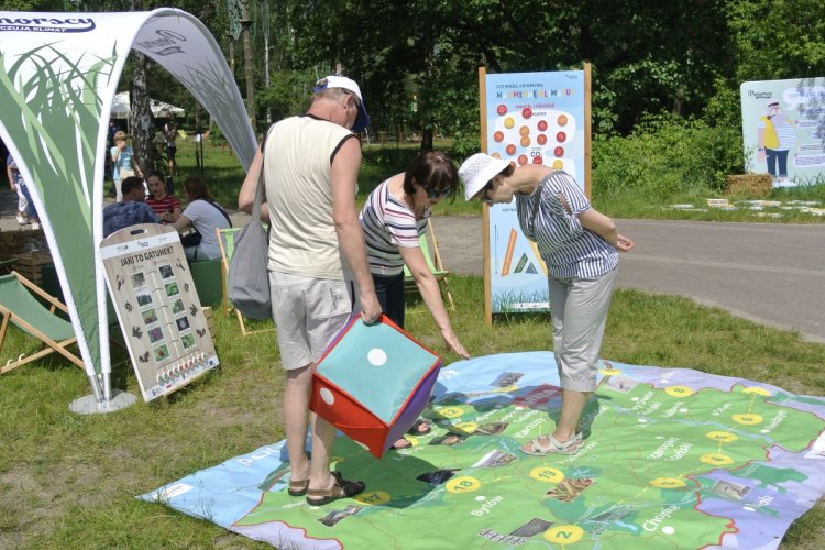 Trzy osoby stoją na planszy gry wielkoformatowej rozłożonej na trawniku