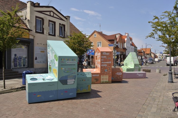 Interaktywna wystawa plenerowa w Łebie, na głównej ulicy w  Łebie stoją trzy bryły tworzące wystawę oraz ławka