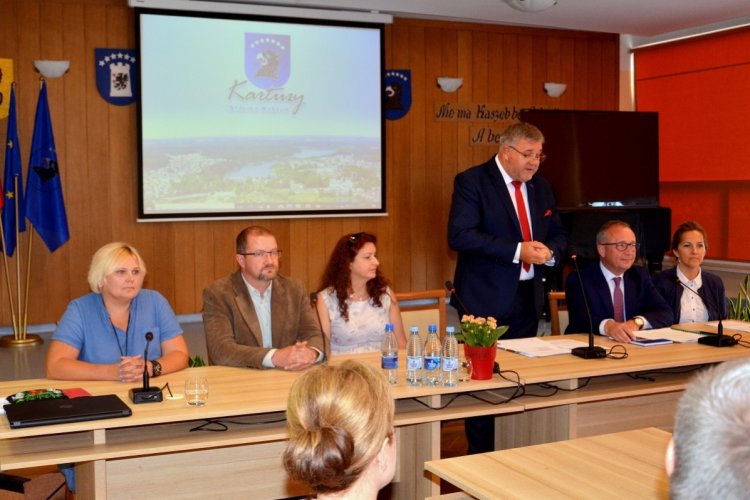 Konferencja poświęcona przystąpieniu gminy Kartuzy do ostatniego etapu rekultywacji i oczyszczania kartuskich jezior; na zdjęciu stół prezydialny, siedzą przy nim prelegenci