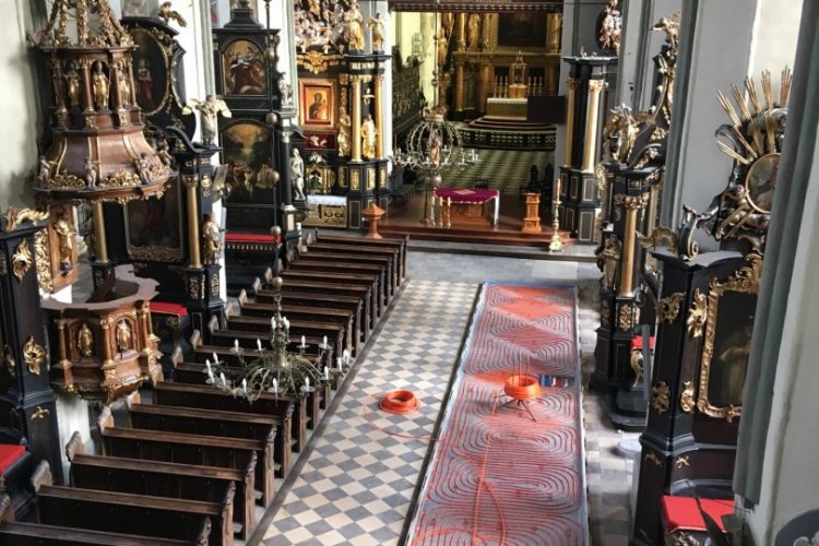 Ogrzewanie podłogowe zamontowane zostało w podeście pod ławkami, widok na wnętrze świątyni z góry 